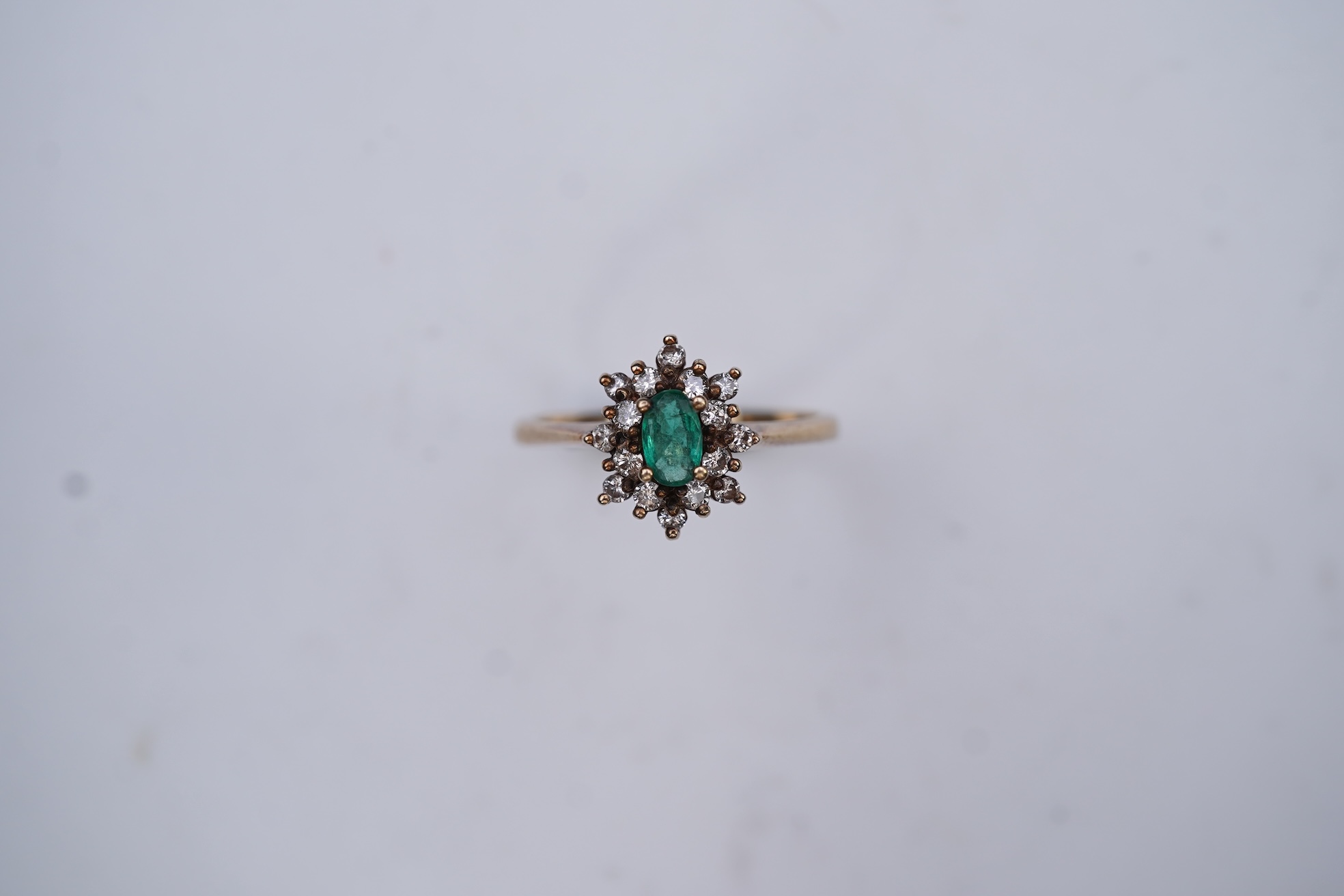 An emerald and diamond cluster ring